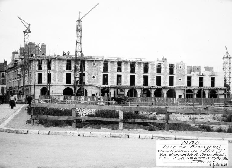 Vue d'ensemble de la rue Denis-Papin depuis le sud-ouest, début des travaux de l'étage attique, 18-07-1948. (Archives départementales de Loir-et-Cher, Blois, 1195 W 44).