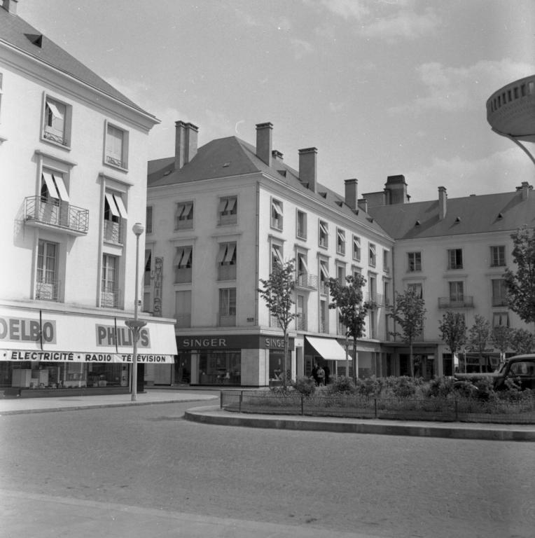 Vue des façades de l'îlot M sur la place, mai 1954. (ministère de l'écologie, du développement durable, des transports et du logement, Fonds M.R.U., cliché n°20380). ; Vue des façades donnant sur la place de la Résistance, 1954. (ministère de l'écologie, du développement durable, des transports et du logement, Fonds M.R.U., cliché n°20380).