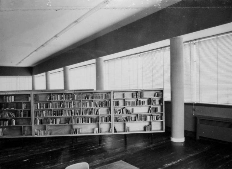 Vue des rayonnages disposés en épi dans la salle de prêt de l'aile ouest, [1958]. (archives départementales d'Indre-et-Loire, Fonds Arsicaud 5 Fi P126, cliché n°13688-8). ; Vue des rayonnages disposés en épi dans la salle de prêt, [1958]. (archives départementales d'Indre-et-Loire, Fonds Arsicaud 5 Fi P126, cliché n°13688-8).