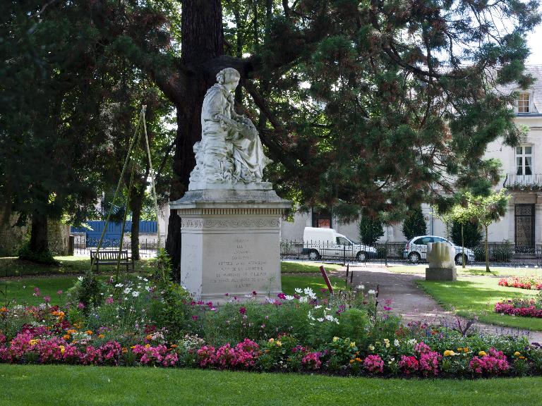 Vue générale du square George-Sand avec le monument de trois quarts arrière et la rue de Belgique en arrière-plan.