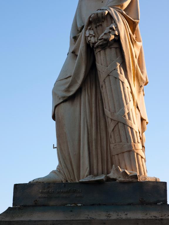 Détail des attributs du côté gauche de la statue (couronne brisée, faisceau surmonté d'une couronne de chêne) et de la marque de fondeur sur la plinthe droite : "MAURICE DENONVILLIERS/ SERMAIZE-SUR-SAULX MARNE".