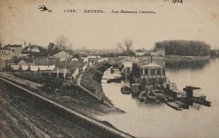 Linge séchant sur le port Neuf, vue prise vers l'aval. Au premier plan, la cale d'abordage séparant le port de Médine et le port Neuf. Carte postale ancienne. (archives municipales de Nevers, 5 Fi 1979).