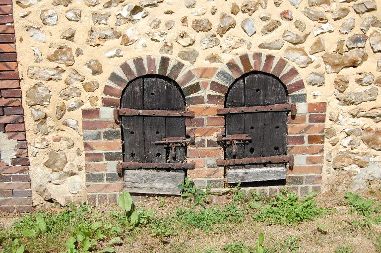 Le Charmois, mise en oeuvre en moellons de silex, encadrements en brique. ; Bâtiment secondaire, détail des portes de niches à chien.