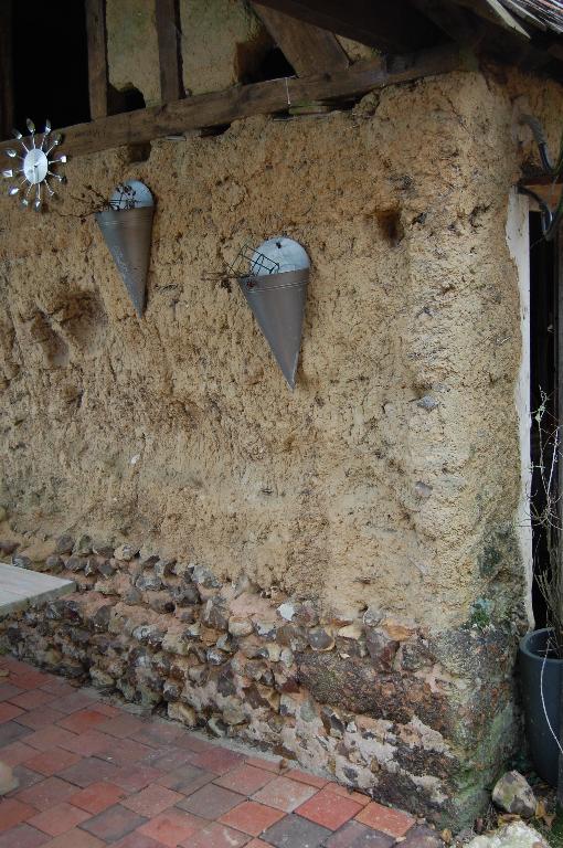 Fournil et toit à porcs, détail de la mise en oeuvre. ; La Léonie, mise en oeuvre en terre crue (bauge) sur solin maçonné en moellons de silex.