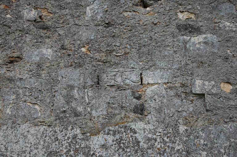 Élévation nord, détail de pierres scuptées remployées dans le mur obstruant le passage vers l'ancien transept détruit.