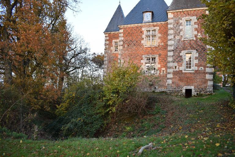 Vue partielle depuis l'ouest : douves sèches et façades à décor de brique, croisées et demi-croisées.