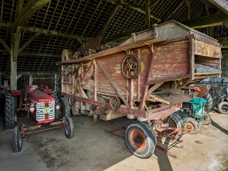Batteuse et tracteur des années 1950 conservée sous le hangar.