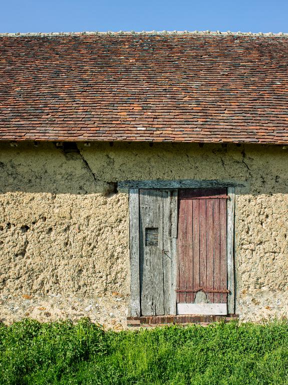Ferme n°7, façade nord, vue de détail de la mise en oeuvre en terre crue et de la porte de grange.