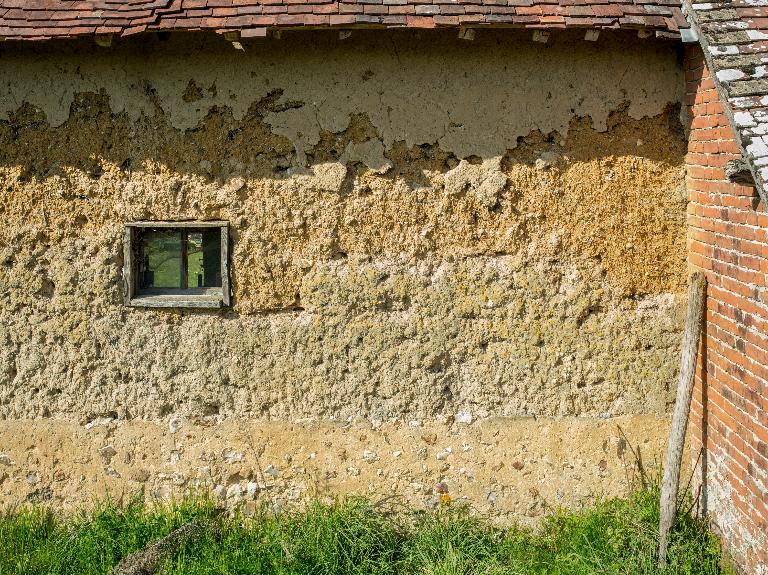 Mise en oeuvre en terre crue (bauge), aux Houdraises. ; Ferme n°7, façade nord, vue de détail de la mise en oeuvre en terre crue.