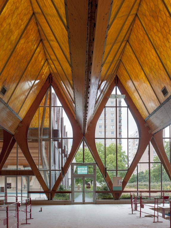 Vue de détail des verrières avec huisseries en aluminium, de la charpente en lamellé-collé et de la toiture en coques de plastique.