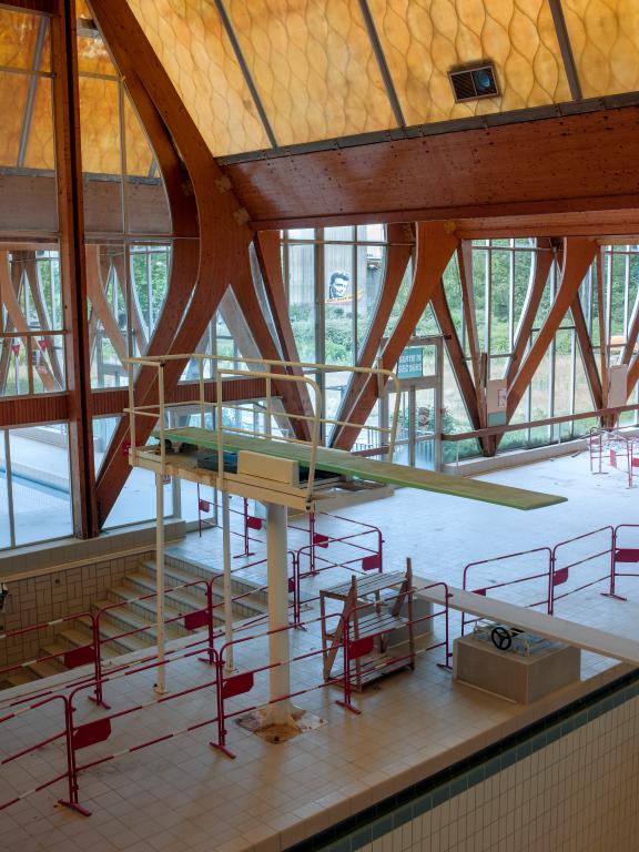 Vue du plongeoir au premier plan et de l'escalier droit donnant accès aux vestiaires situés dans le sous-sol semi-enterré au second plan prise depuis la terrasse.
