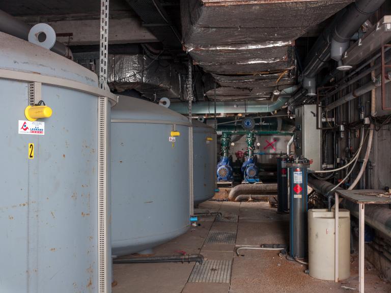 Vue intérieure des locaux techniques avec les bacs de filtration à gauche et les pompes au fond (sous-sol semi-enterré).