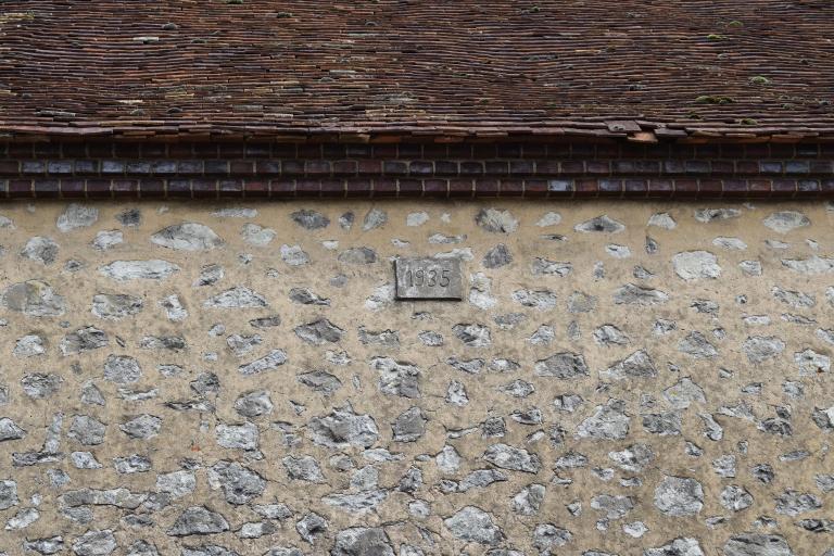 Bâtiment d'exploitation est, date 1935 portée sur une plaque cimentée dans le parement.
