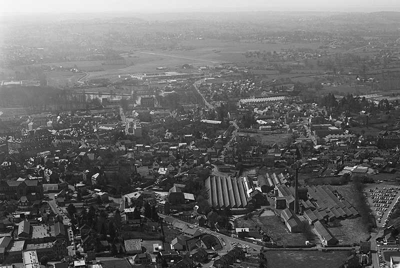 Vue aérienne de Flers. Au 1er plan, usine de la Planchette. A gauche de la cheminée : tissage (commune de Flers), à droite : filature (commune St-Georges-des-Groseillers).