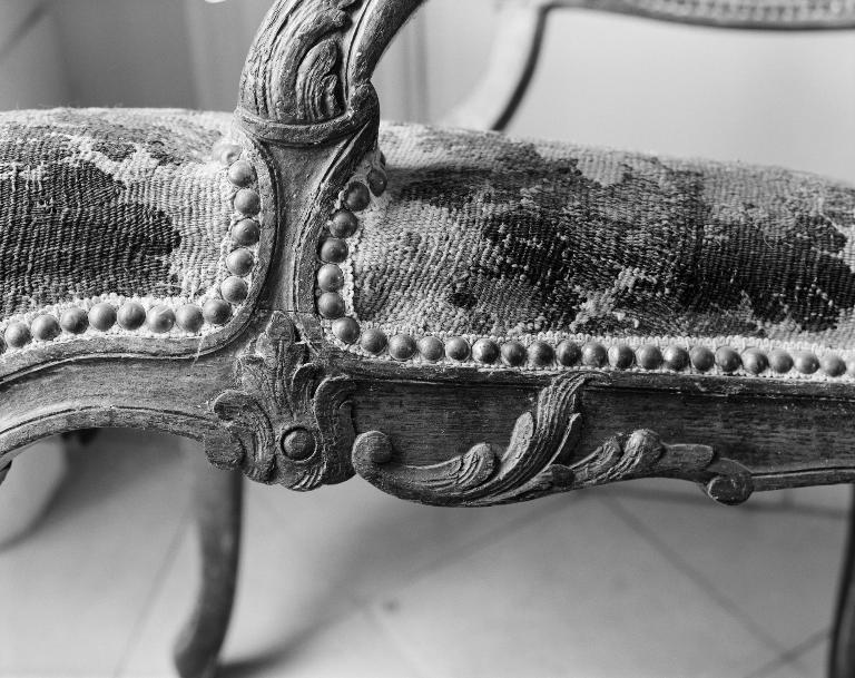 Détail du fauteuil : décor sculpté à la jonction de la ceinture et de la console d'accotoir. 