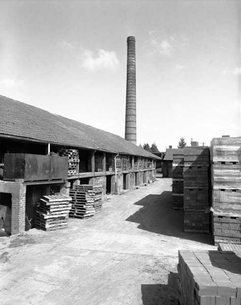 Bâtiment du four continu à galeries. Cheminée d'usine et aire de stockage.