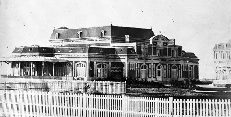 'Vue de la façade postérieure du casino de Deauville.- Photographie ancienne, tirage papier albuminé contrecollé sur page d''album, n. et b., 22 x 14,5 cm, n.s., n.d., vers 1870, tirée de : Album photographique de Madame Berteau (Musée municipal, Villa Montebello, Trouville-sur-Mer).'