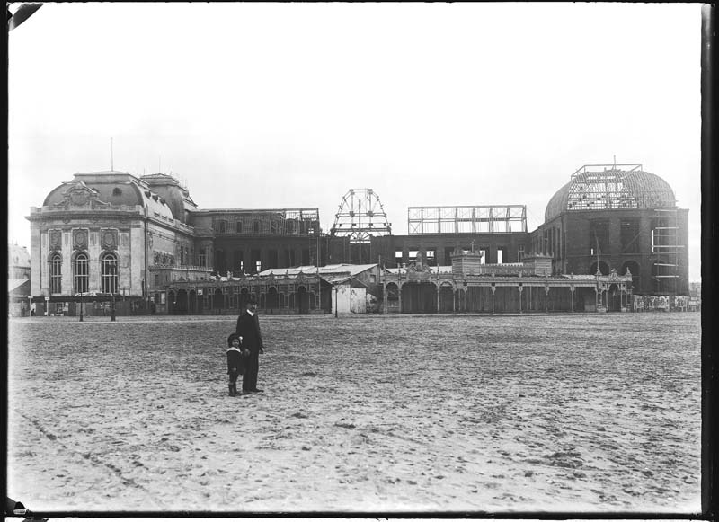 'Chantier de construction. Casino de Trouville. Vue prise de la plage, avec homme et fillette poosant. Vue d''ensemble de la façade nord-ouest.- Photographie ancienne, n.s., n.d., 1912. Tirage n. et b. d''après plaque de verre gélatino-bromure d''argent (négatif), 13 x 18 cm. (Musée municipal, Villa Montebello, Trouville-sur-Mer. 006.1.49).'