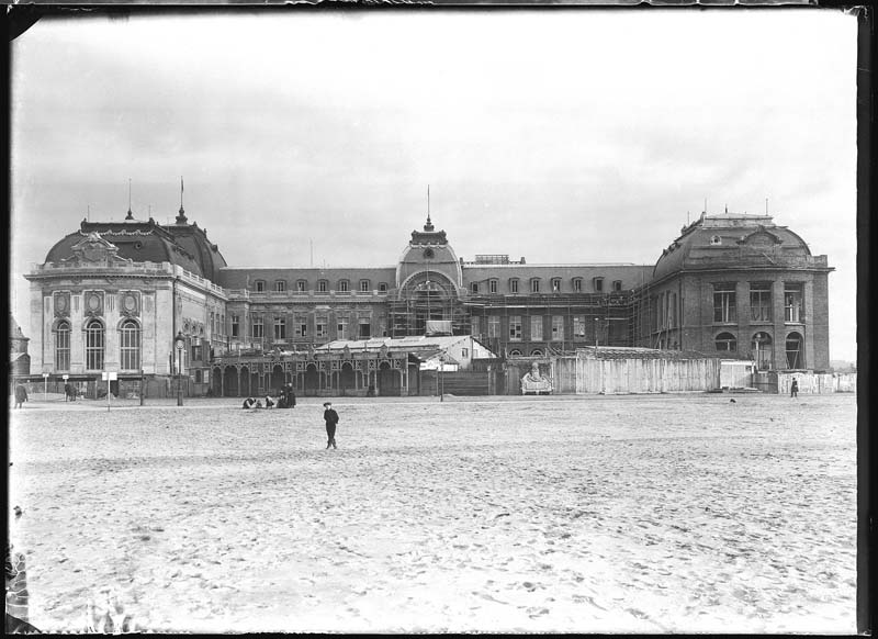 'Chantier de construction. Casino de Trouville. Vue prise de la plage, avec les baraques de l''Eden. Vue d''ensemble de la façade nord-ouest.- Photographie ancienne, n.s., n.d., 1912. Tirage n. et b. d''après plaque de verre gélatino-bromure d''argent (négatif), 13 x 18 cm. (Musée municipal, Villa Montebello, Trouville-sur-Mer. 006.1.68).'