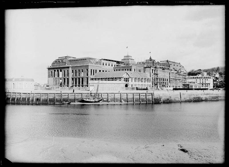 'Chantier de construction. Casino de Trouville. Vue prise de Deauville. Vue des façades sud-ouest et sud-est.- Photographie ancienne, n.s., n.d., 1912. Tirage n. et b. d''après plaque de verre gélatino-bromure d''argent (négatif), 13 x 18 cm. (Musée municipal, Villa Montebello, Trouville-sur-Mer. 006.1.94).'