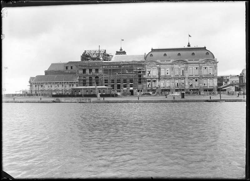 'Chantier de construction. Casino de Trouville. Vue prise de Deauville. Vue de la façade sud-est.- Photographie ancienne, n.s., n.d., 1912. Tirage n. et b. d''après plaque de verre gélatino-bromure d''argent (négatif), 13 x 18 cm. (Musée municipal, Villa Montebello, Trouville-sur-Mer. 006.1.100).'