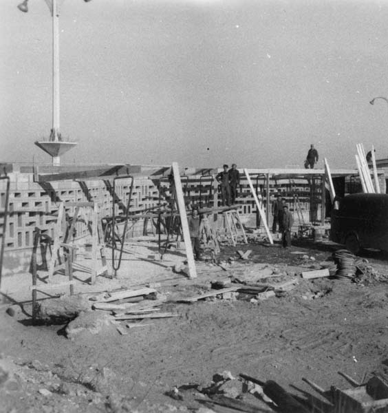 'Reconstruction du casino. Mur reliant le casino au pavillon d''information. Vue d''ensemble prise du sud-ouest.- Photographie ancienne, n.s., 15 mars 1957, [date manuscrite]. Tirage original sur papier brillant contrecollé sur carton, n. et b., 6,2 x 6,2 cm. (AC Ouistreham).'