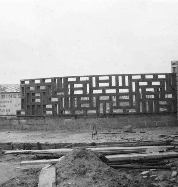 'Reconstruction du casino. Mur reliant le casino au pavillon de l''information, vue prise du sud.- Photographie ancienne, n.s., 1er février 1957, [date manuscrite]. Tirage original sur papier brillant contrecollé sur carton, n. et b., 6,2 x 6,2 cm. (AC Ouistreham).'