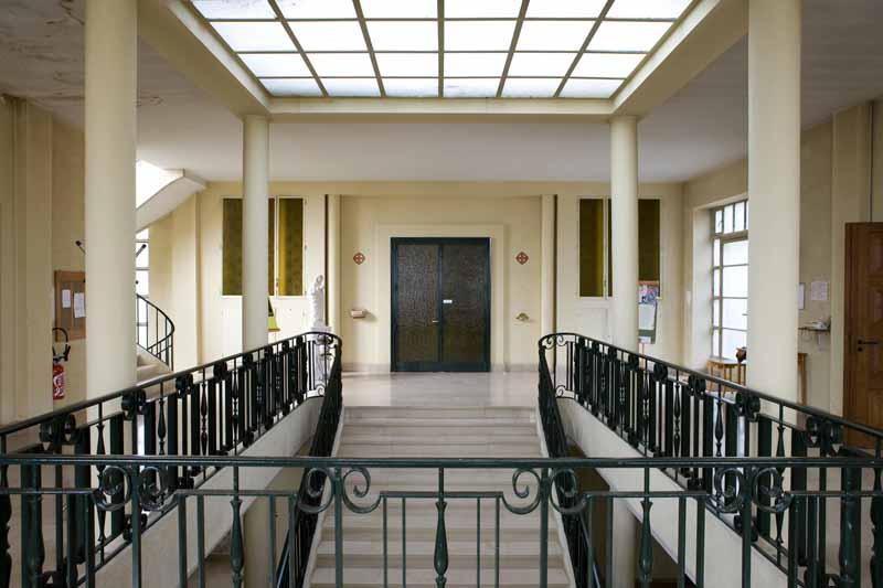 Chapelle du Bon Sauveur, vue intérieure : escalier d'honneur, vue prise depuis l'étage. Rampe en fer forgé, réalisée par l'atelier parisien du décorateur Raymond Subes.