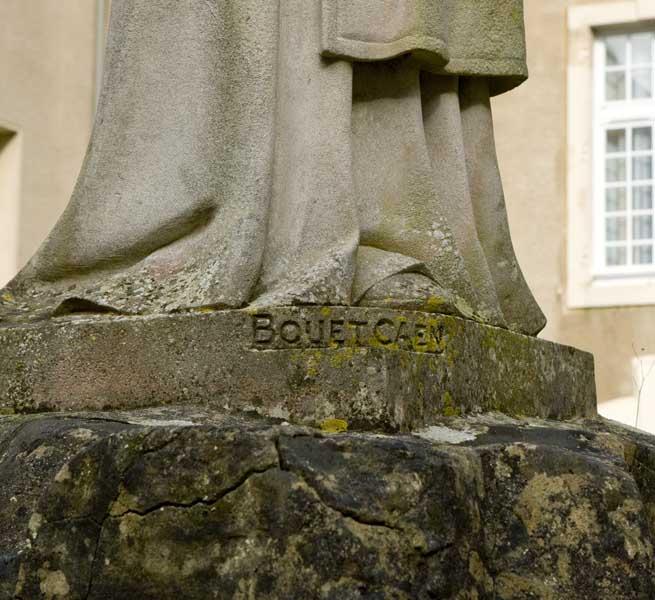 Bâtiment de la Maison de retraite 'Elisabeth de Surville', anciennement bâtiment de la Communauté. Monument du Centenaire (1937), situé dans la cour. Détail de la signature (BOUET CAEN), sur le socle de la figure centrale.