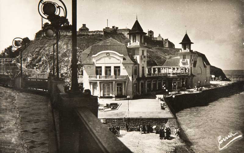 'N° 1. Granville (Manche). Les Hôtels et le Casino, vue prise de la Terrasse du Normandy Hôtel. [Vue prise du nord-est, 3e casino].- Carte postale, Emma Bernard éd., n.d., après 1925 [date d''aménagement de la place], n. et b., 17,7 x 8,8 cm. (Musée du Vieux Granville, Granville).'