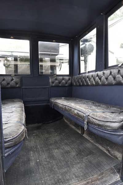 Vue intérieure de l'omnibus : banquettes en vis-à-vis, capitonnées de cuir noir.