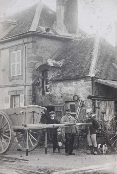 Henri Oréal (au centre), posant près d'un tombereau de sa fabrication, devant son atelier.- Photographie, milieu 20e siècle (Collection particulière G. Pottier).