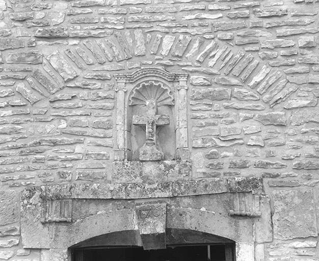 Niche surmontant le portail. Croix de pierre ornée d'un ostensoir en relief.