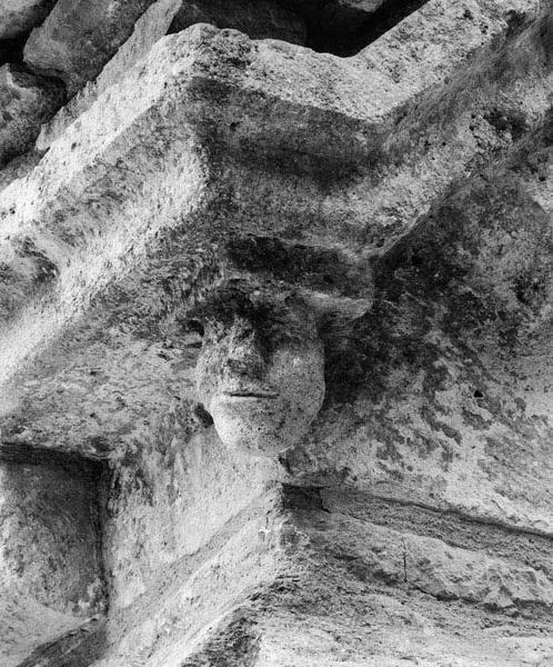 Bas-côté gauche : détail de la tête sculptée sur l'angle antérieur, sous la corniche.