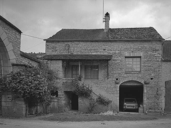 Portail et maison bordant la cour à gauche.