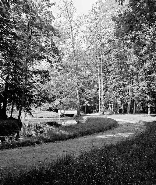 Allée bordant le lac avec le petit pont de pierre à l'arrière-plan.