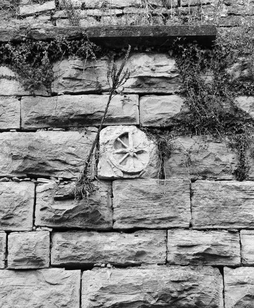 Grosse Tour, appelée aussi bastion Calvet, depuis le fossé, détail : pierre sculptée d'une roue, emblème du gouverneur de La Trémouille, en poste lors de l'édification de la tour (1993).