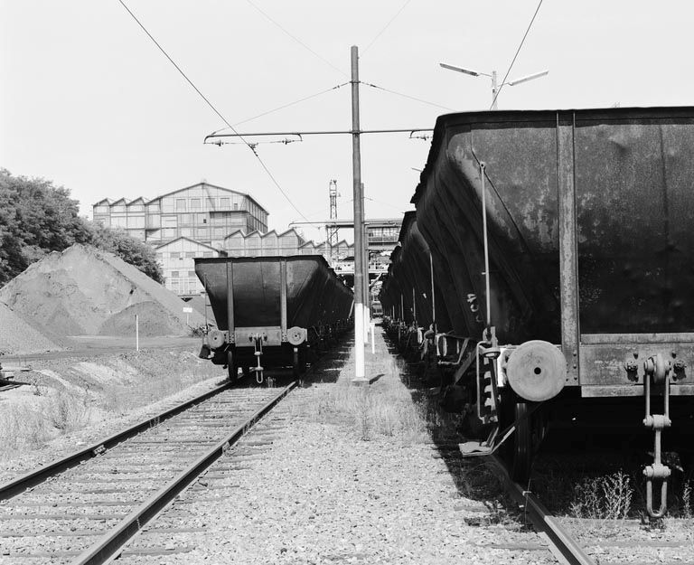 Wagons de transport de charbon en stationnement sur une ligne électrifiée.