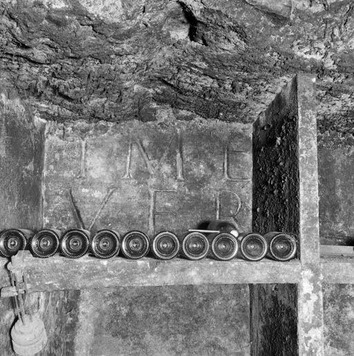 Bâtiment sud : cave, caveron du 2e vaisseau, détail d'une pierre avec inscription remployée dans les casiers à bouteilles