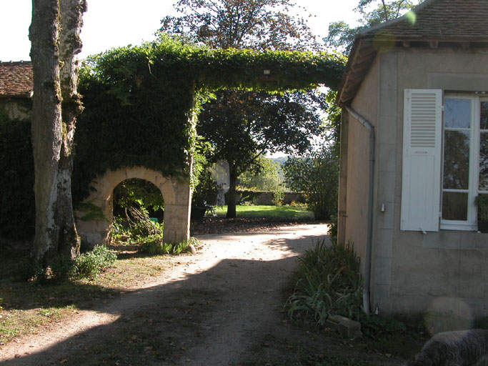 Vue des portails d'entrée de la maison du maître de forge. Il y a une charretière sur le côté.