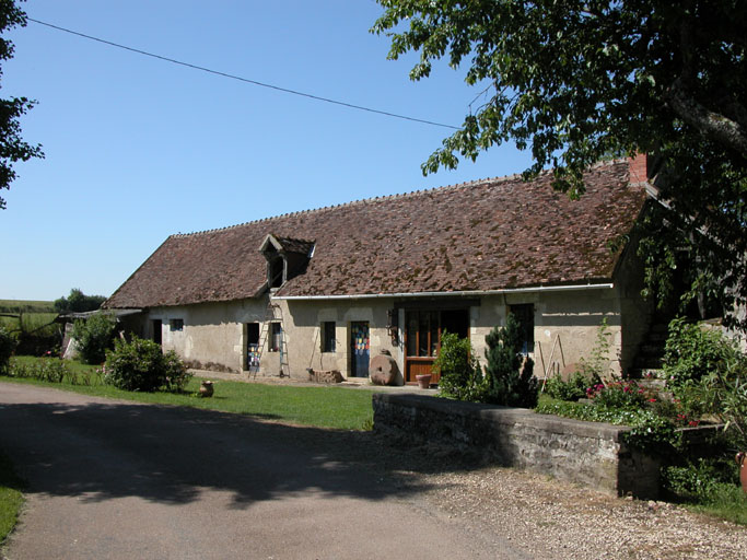 Vue de trois quarts du logement d'ouvriers par la route.