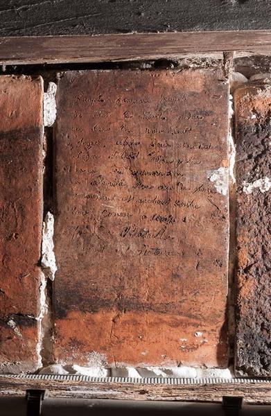 Corps de bâtiment principal : tuile encastrée dans le mur droit de l'escalier de la cave.