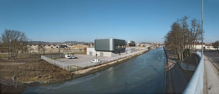 Traversée du canal à Dijon : le canal en amont du pont permettant le passage des boulevards John-Kennedy et Maillard. De gauche à droite : entrepôts SNCF en cours de reconversion ; poste d'aiguillage informatisé de la SNCF Thierry Sarrat ; port des minoteries dijonnaises (elles-mêmes détruites) ; nouveau pont sur l'écluse 55 ; boulevards John-Kennedy et Maillard.