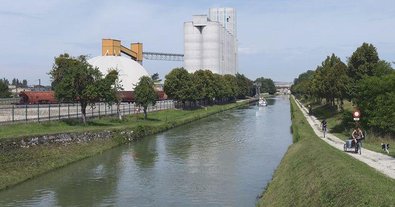 Vue d'ensemble des silos avec accès par pont roulant au canal. A l'extrême-gauche, les voies SNCF.