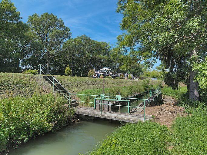 La rigole avec les vannes de régulation. A gauche, le talus du canal.