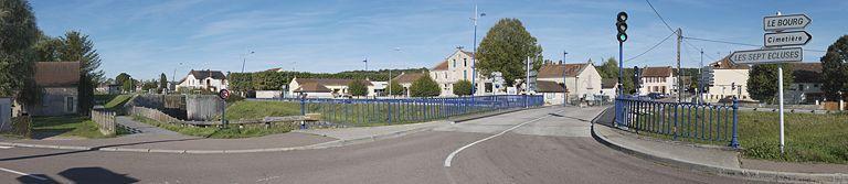 Au premier plan, le pont isolé, ancien pont sur écluse VII. En face du pont : le monument aux morts d'Ecuisses. La mairie est à gauche du pont.