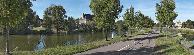 L'ancien château de la Motte-Bouchot : les écuries réaménagées en habitation pour les ouvriers de l'ancienne tuilerie sont installées le long de l'étang de la Motte, parallèlement au canal. Au fond, la mairie.