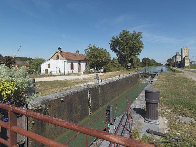 Panorama du site d'écluse pris d'aval, du pont sur écluse. De gauche à droite : site d'écluse, silos. Le bief est vide : on voit la maçonnerie des bajoyers.