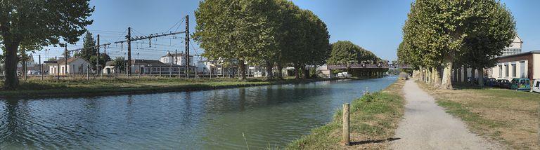 Panorama du canal traversant Migennes en direction de l'Yonne. A gauche, le site SNCF et la gare, la passerelle menant à la gare.