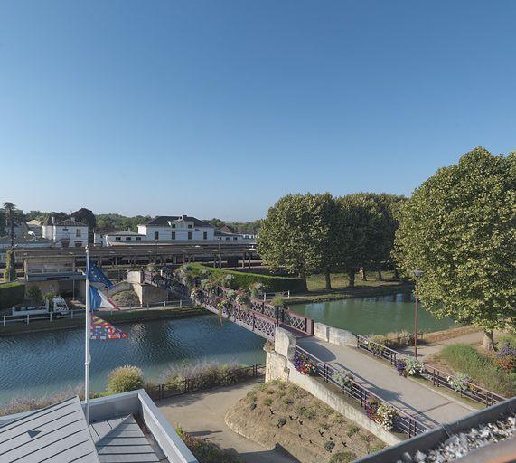 A gauche, le site SNCF et la gare. La passerelle menant à la gare.